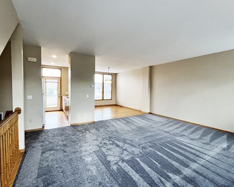 A spacious room with a blue carpet and wooden railings.