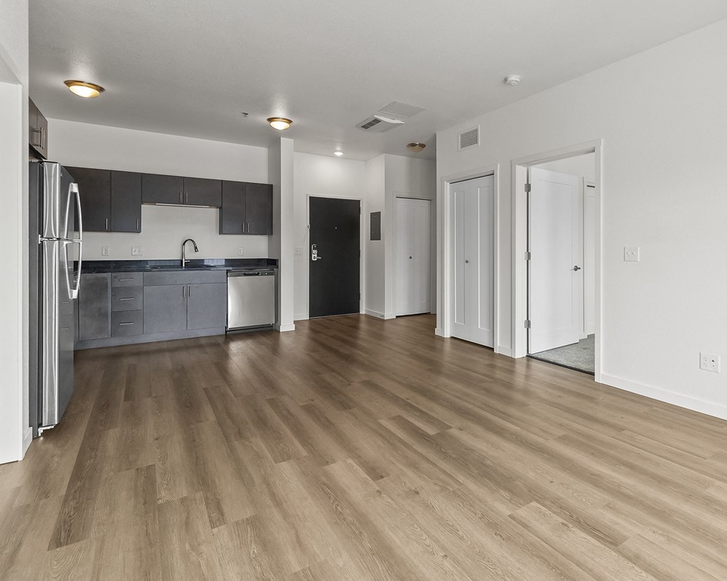 the living room and kitchen of an apartment with wood flooring