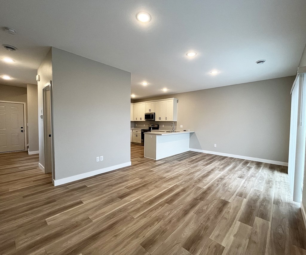 the living room and kitchen of a new home with wood flooring