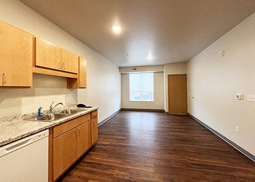 an empty kitchen and living room with wood flooring and a window