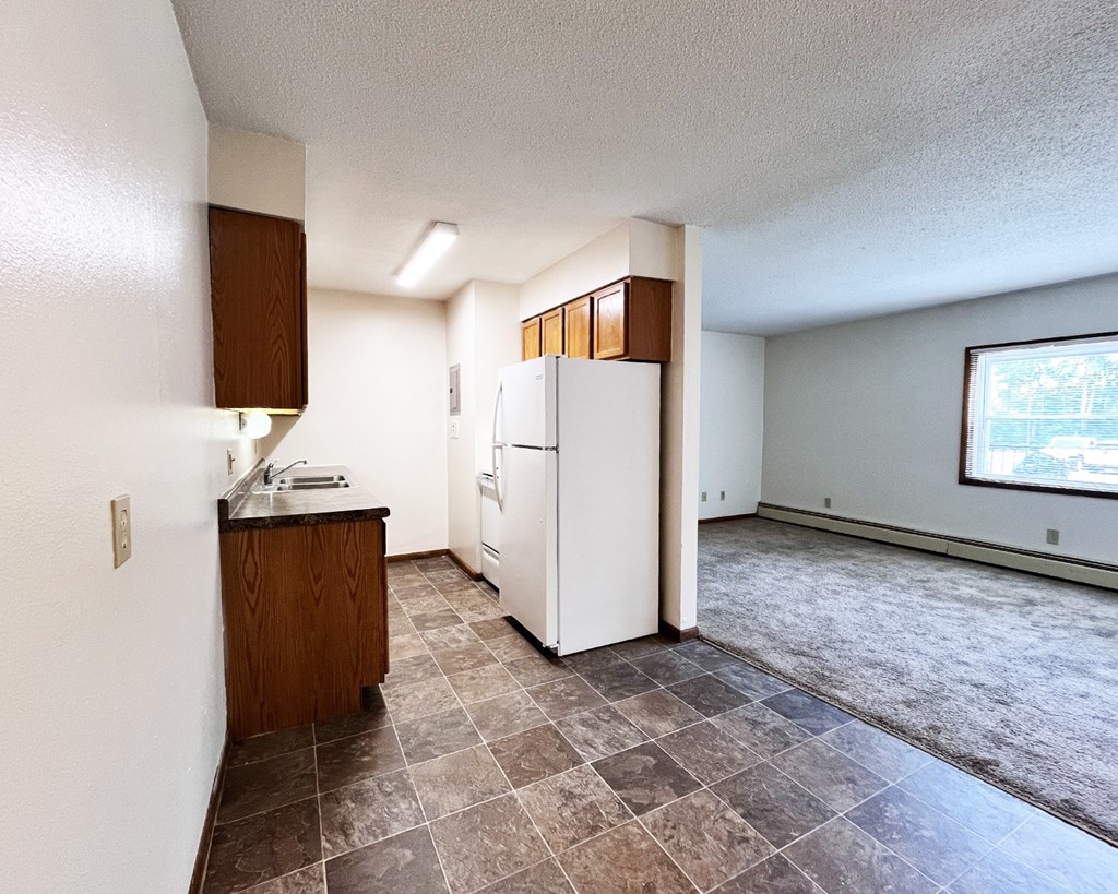A kitchen with a white refrigerator and brown cabinets.