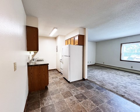 A kitchen with a white refrigerator and brown cabinets.