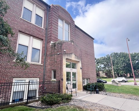 A red brick building with a black iron fence in front.