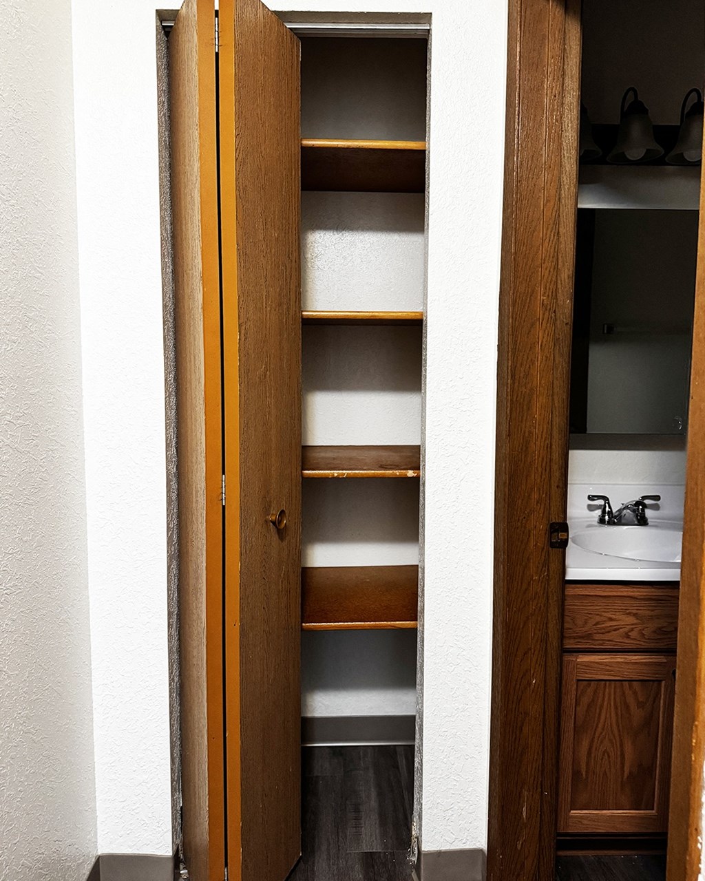 A tall wooden closet with shelves and a mirror.