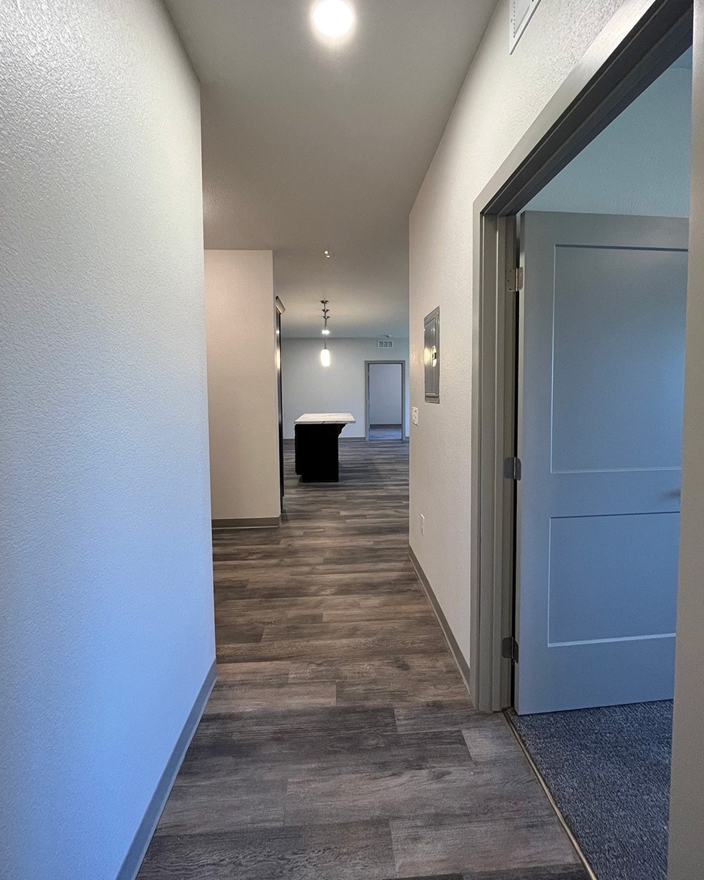 a hallway with a blue door and a door to a room with a table