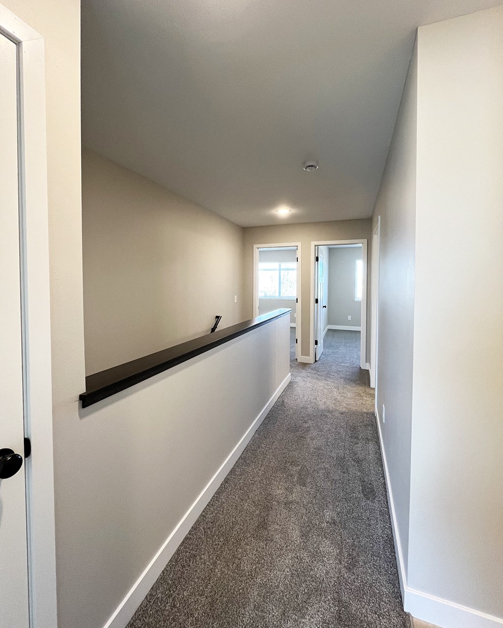 a hallway with white walls and a long white wall with a black ledge and a