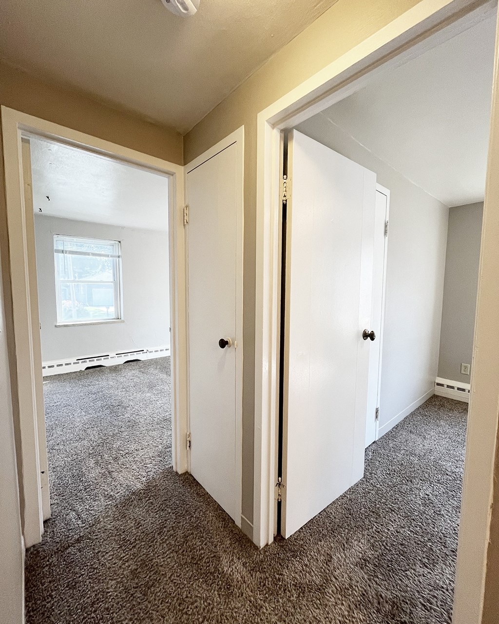 an empty bedroom with two doors and a window