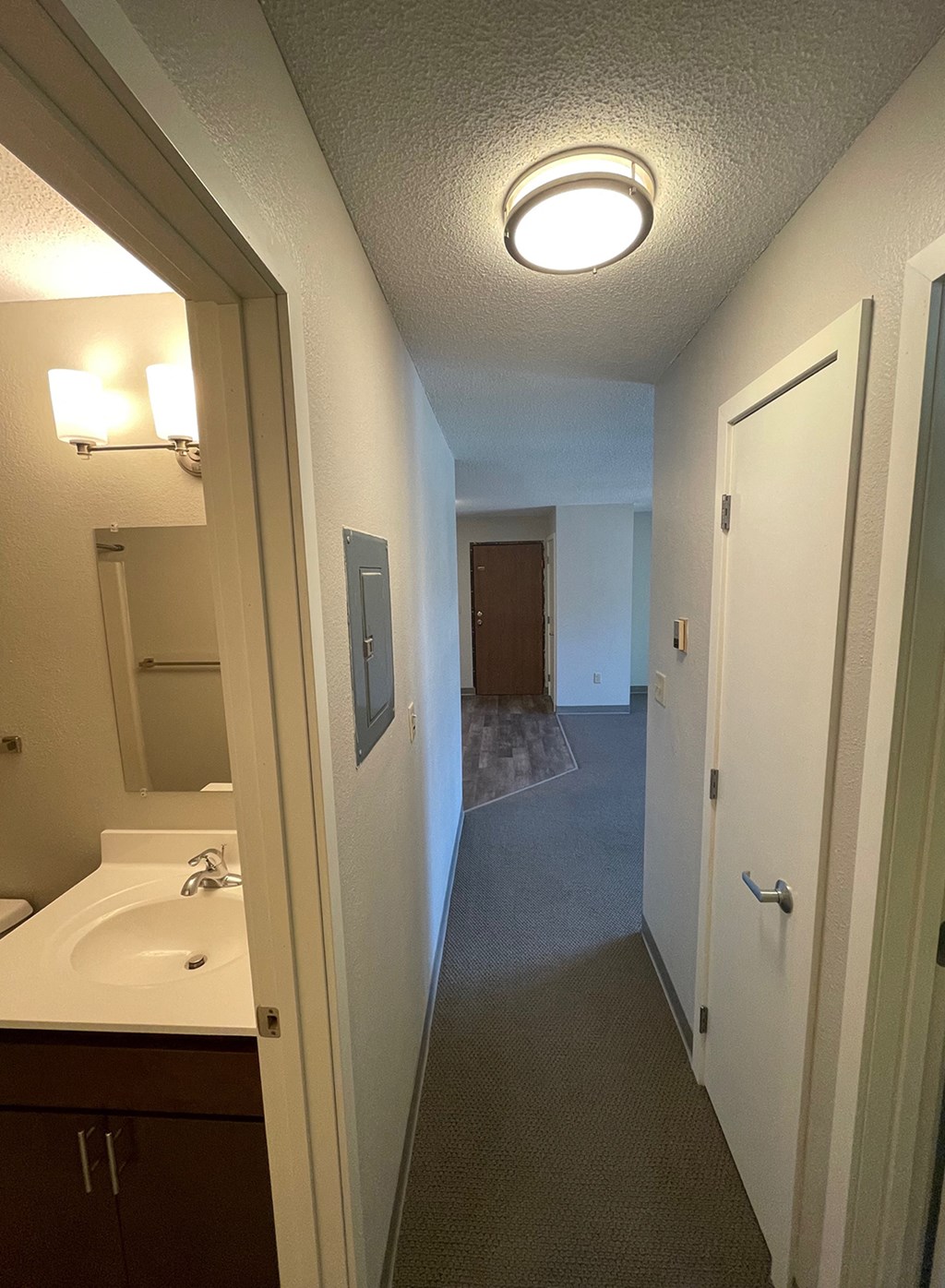 a bathroom with a sink and a mirror and a hallway with a door