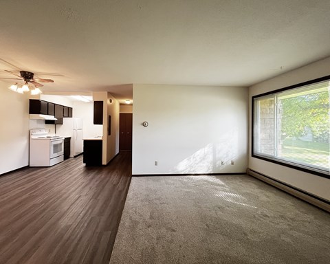 A spacious room with a ceiling fan and a kitchen area in the background.
