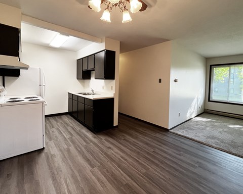 A kitchen with a white refrigerator and black cabinets.
