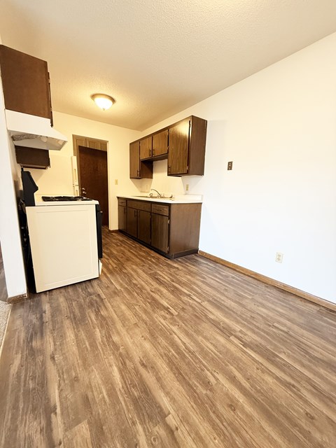 A kitchen with white appliances and wooden floors.