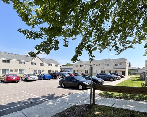 A parking lot with cars and apartment buildings in the background.