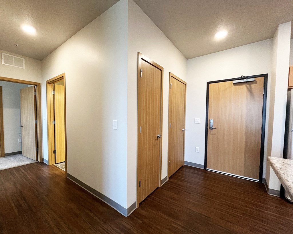 A hallway with three doors and a bench on the right side.