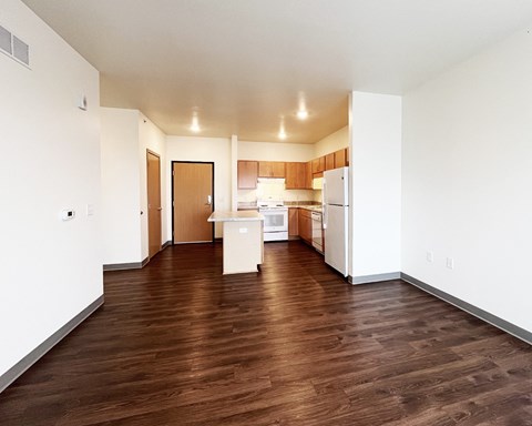 A kitchen with white appliances and wooden floors.