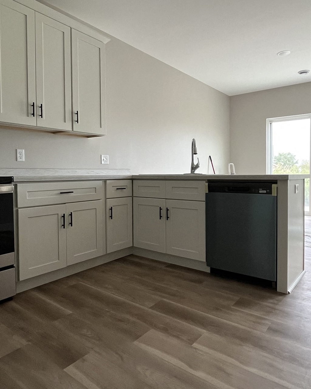 a kitchen with white cabinets and a black dishwasher