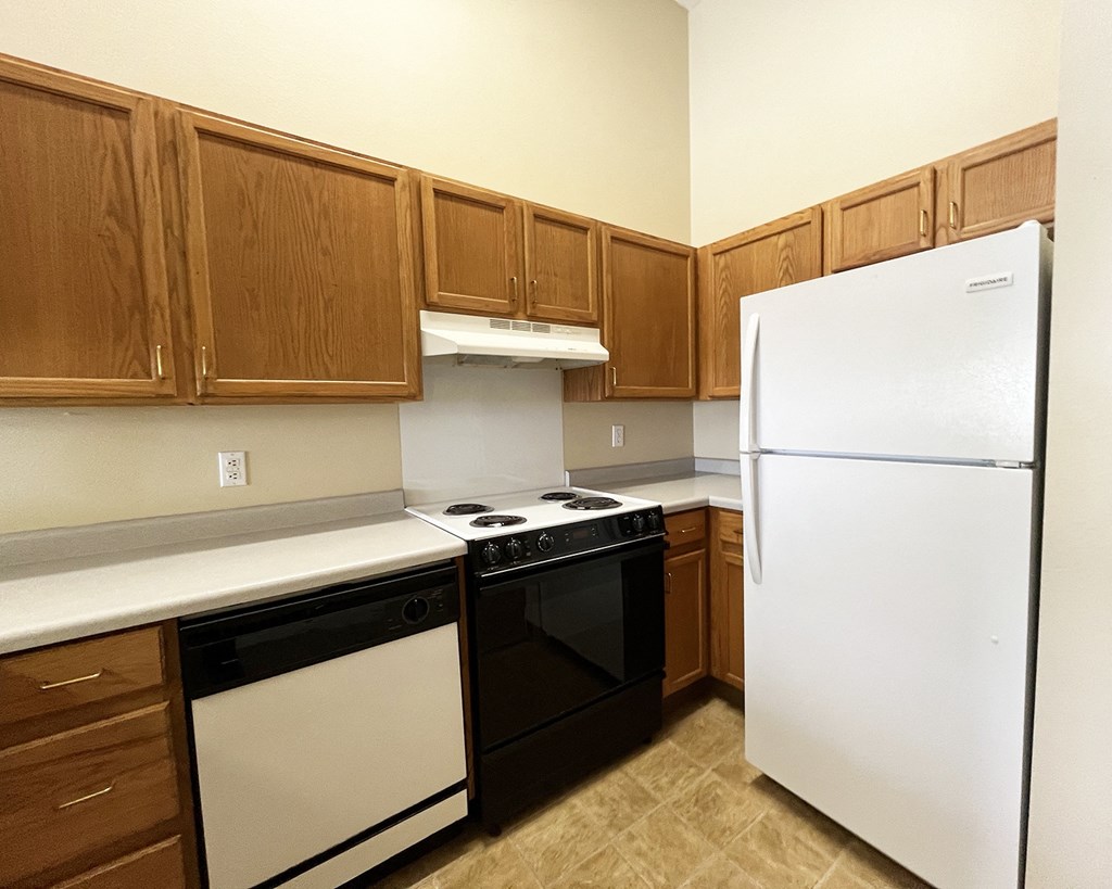 an empty kitchen with white appliances and wooden cabinets