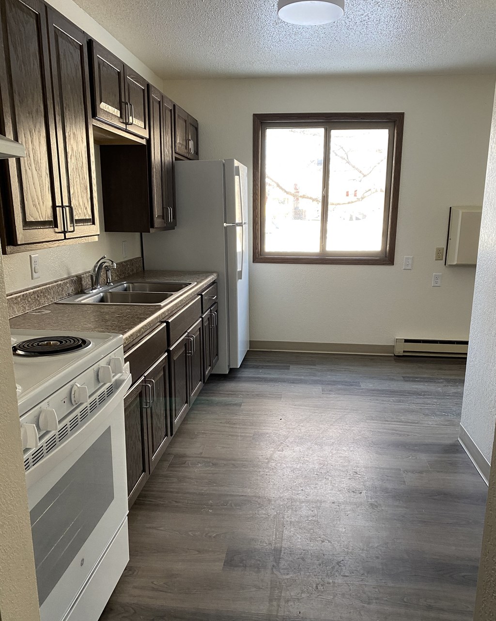 an empty kitchen with a stove refrigerator and sink