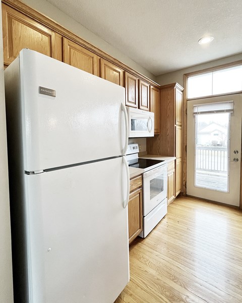 A white refrigerator in a kitchen with wooden cabinets.