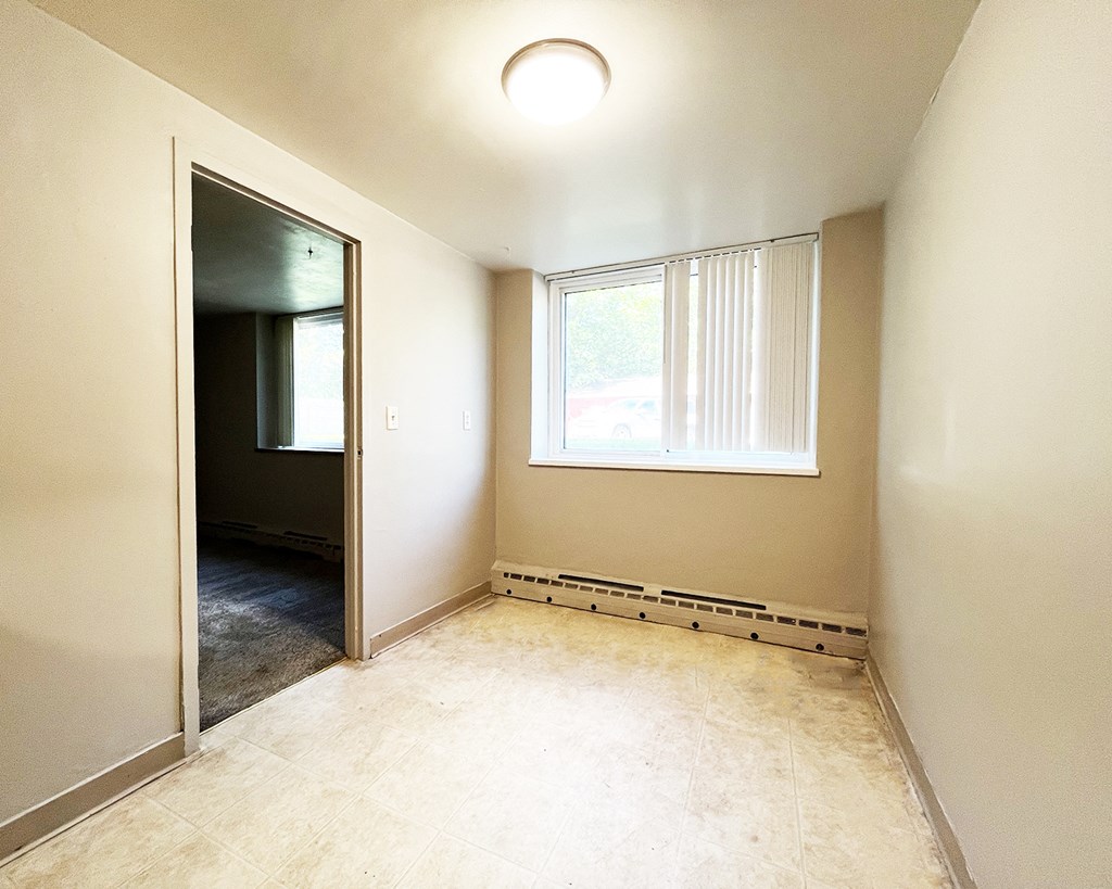 an empty room with a window and a door to a hallway
