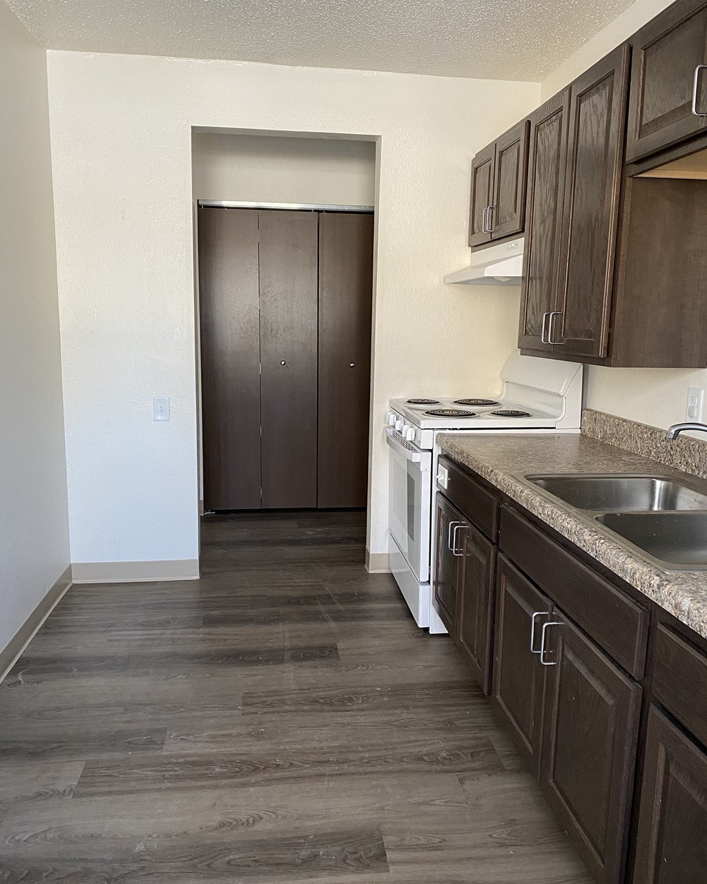 an empty kitchen with wooden cabinets and a white stove and sink