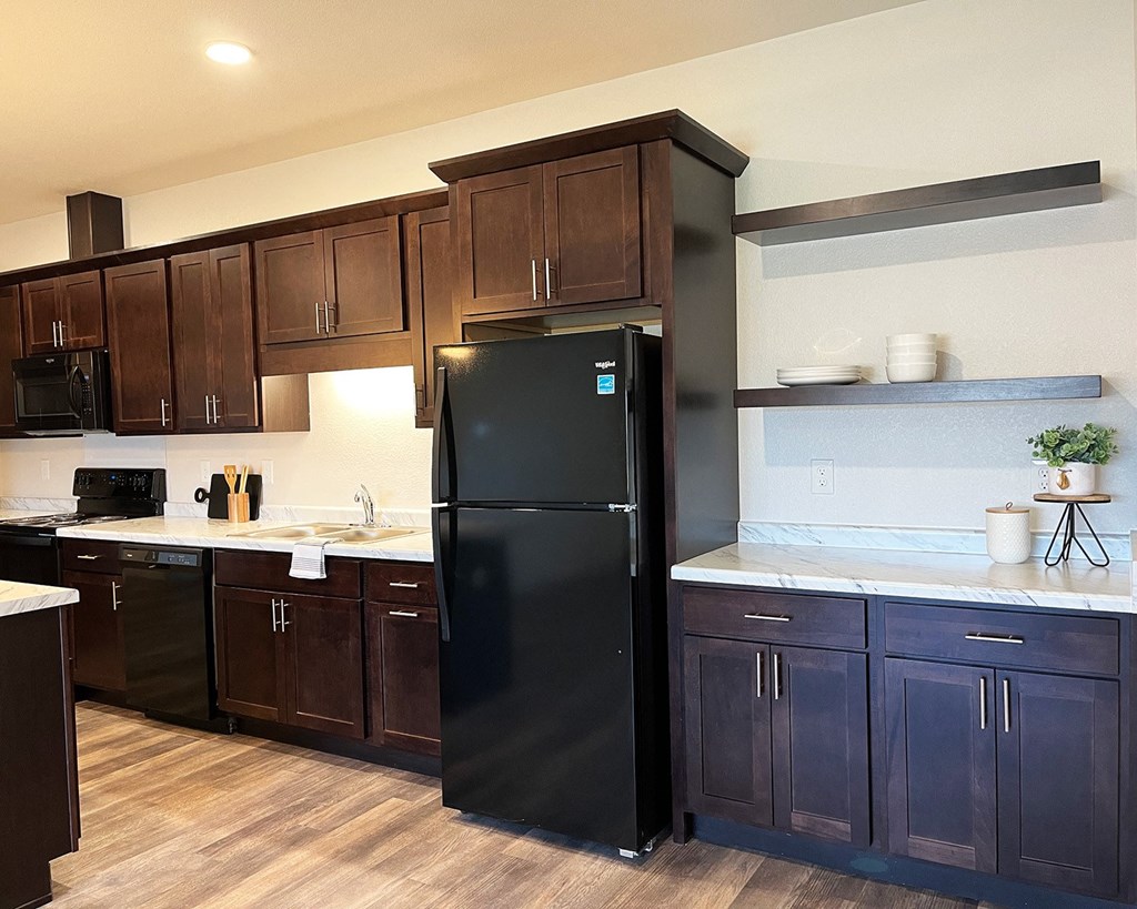 a kitchen with dark cabinets and a black refrigerator