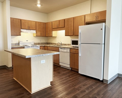 A kitchen with a white refrigerator and wooden cabinets.