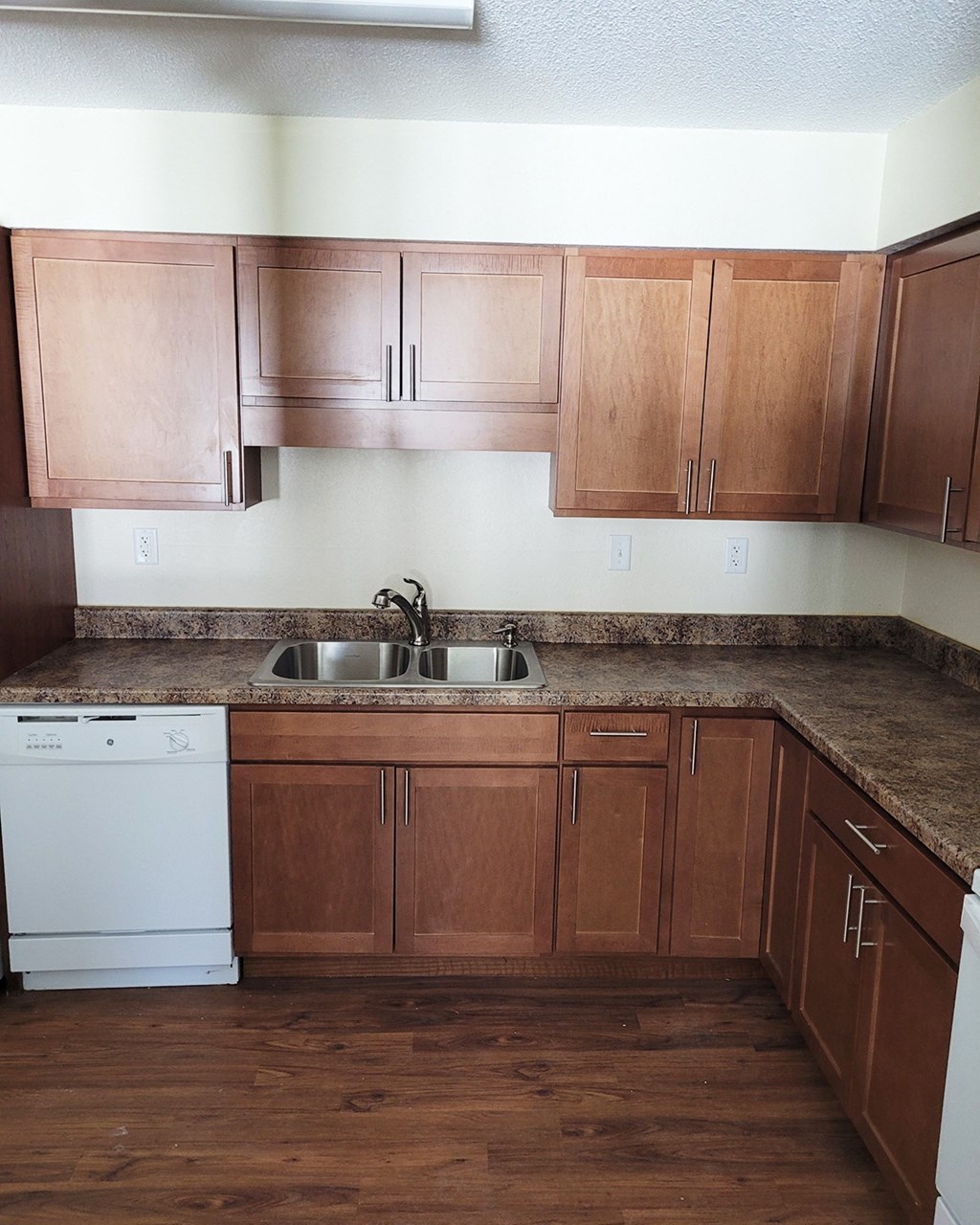 an empty kitchen with wooden cabinets and a sink