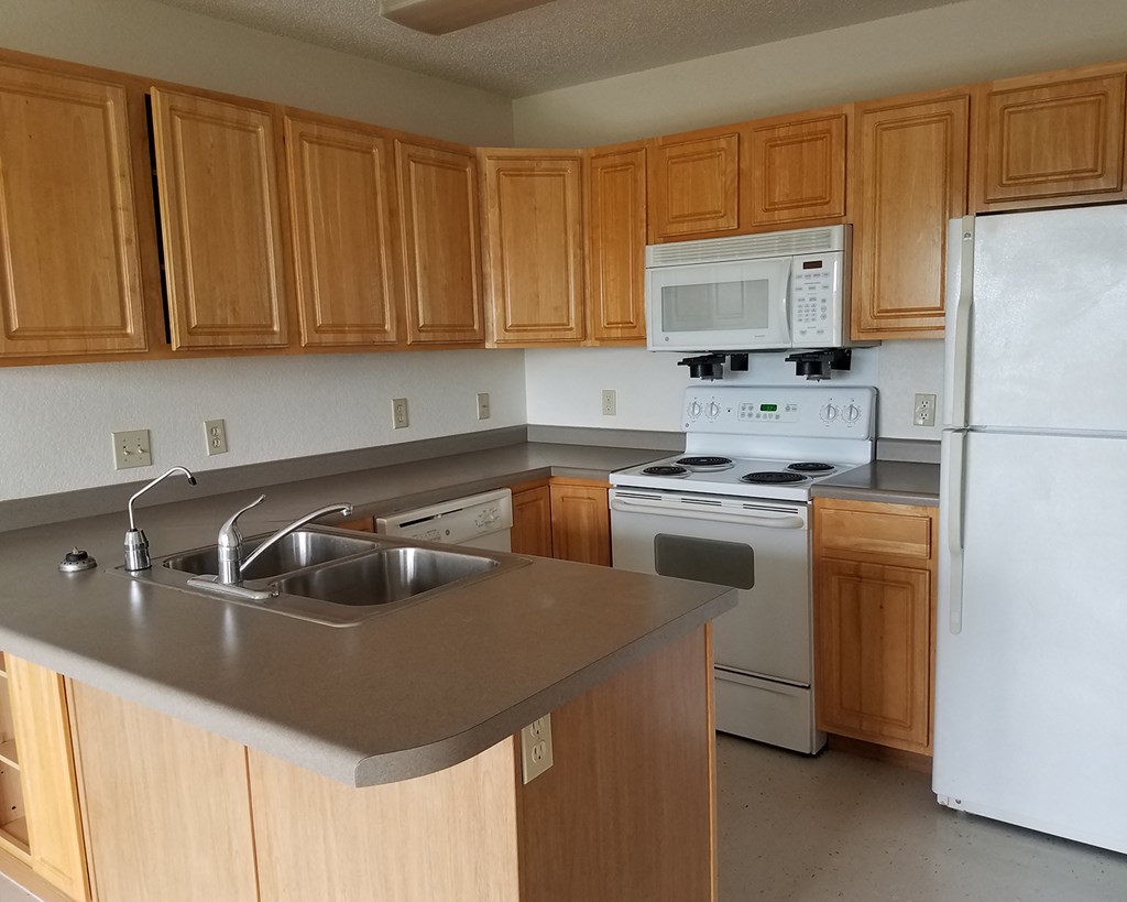 an empty kitchen with wooden cabinets and white appliances