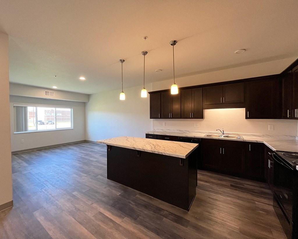 an empty kitchen with dark cabinets and a marble counter top