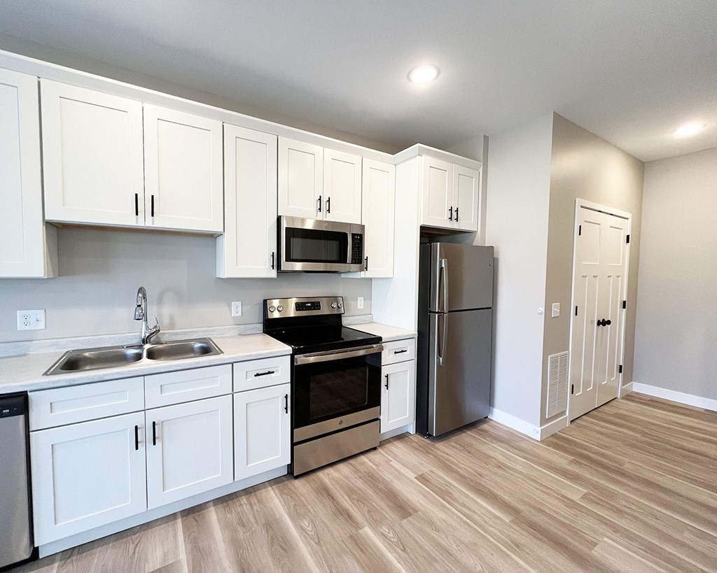 an empty kitchen with white cabinets and stainless steel appliances