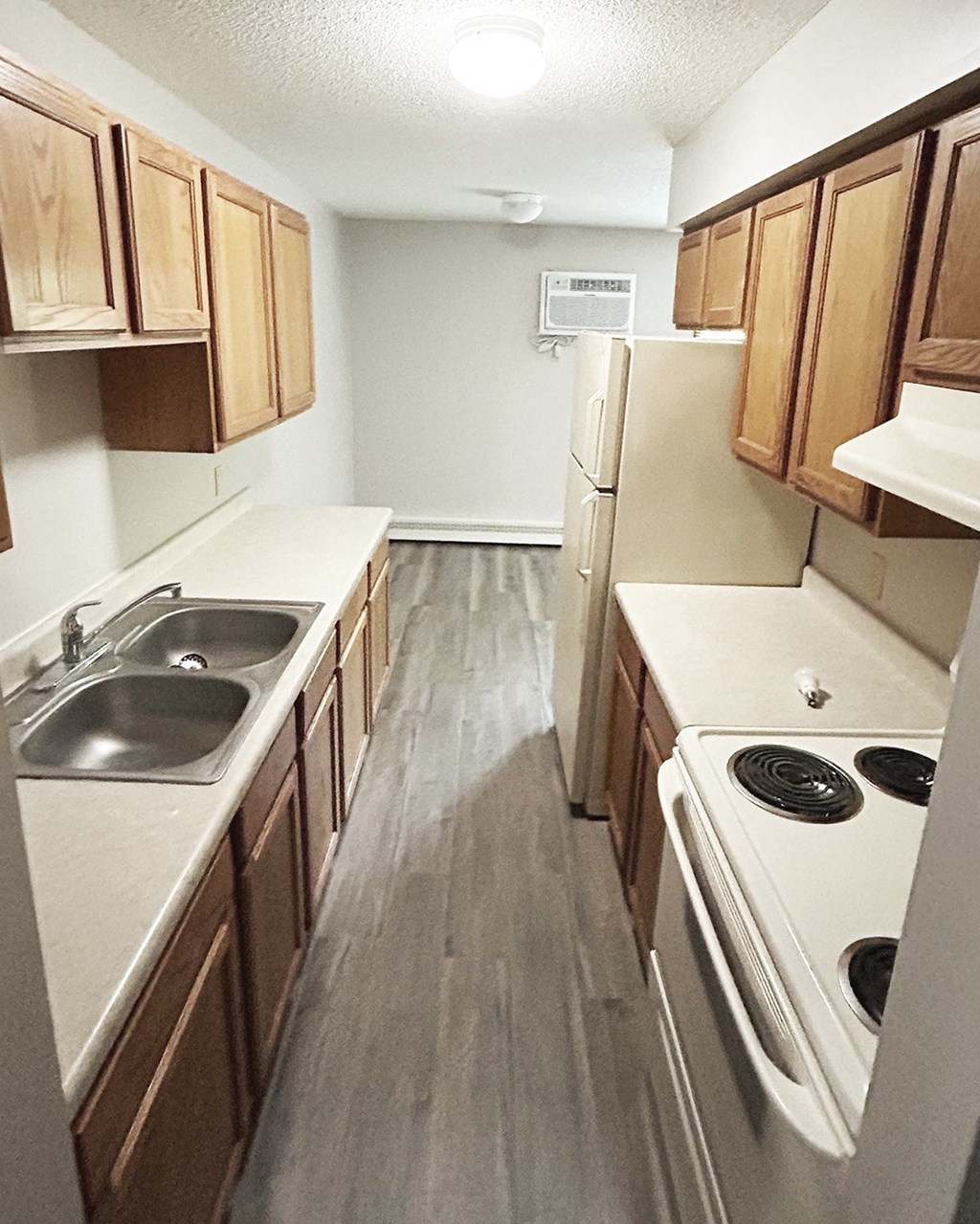 an empty kitchen with wood floors and white appliances