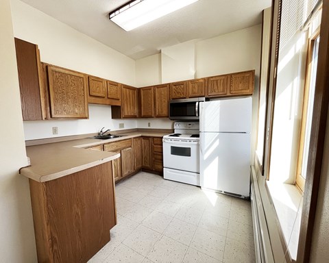 an empty kitchen with white appliances and wooden cabinets