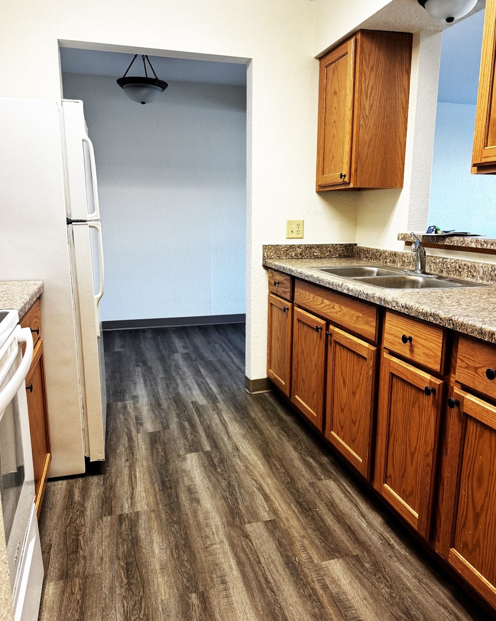 A kitchen with a white refrigerator and wooden cabinets.