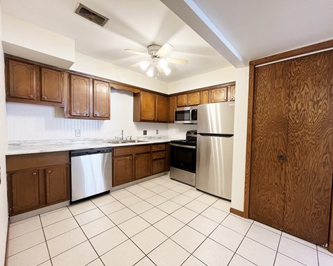 A kitchen with brown cabinets and white appliances.