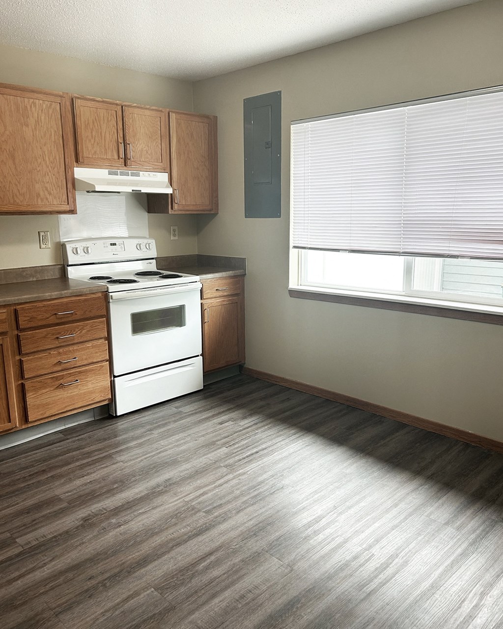 A kitchen with a white stove top oven and wooden cabinets.