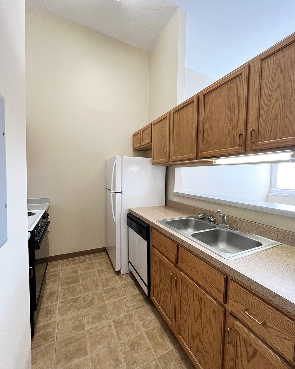 A kitchen with a white refrigerator, black stove, and wooden cabinets.
