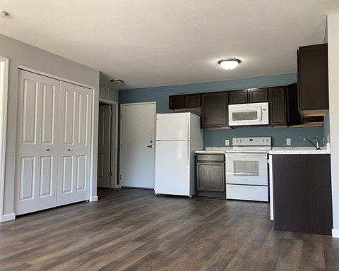 A kitchen with a white refrigerator and wooden floors.