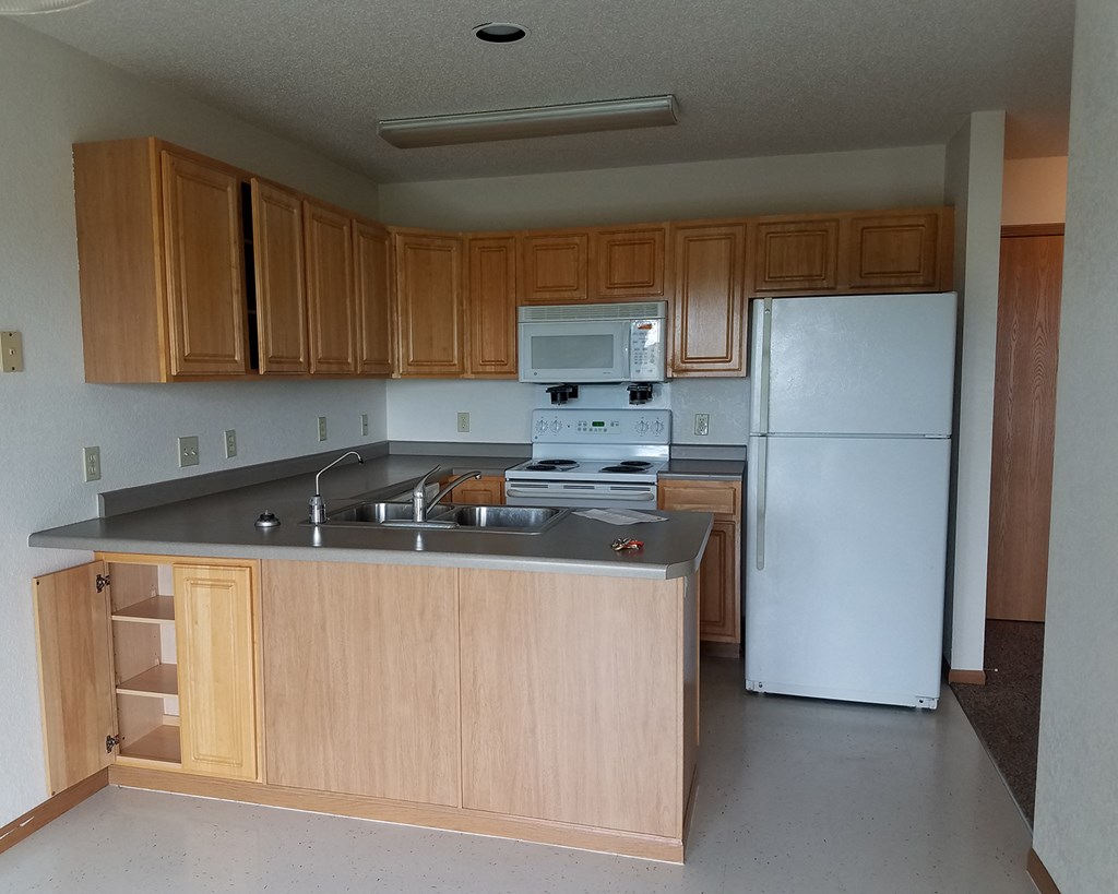 an empty kitchen with wooden cabinets and a white refrigerator