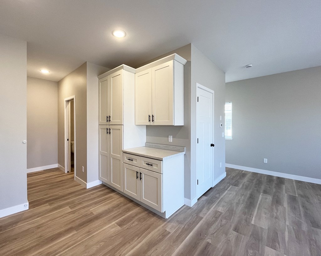 an empty kitchen with white cabinets and a wood floor