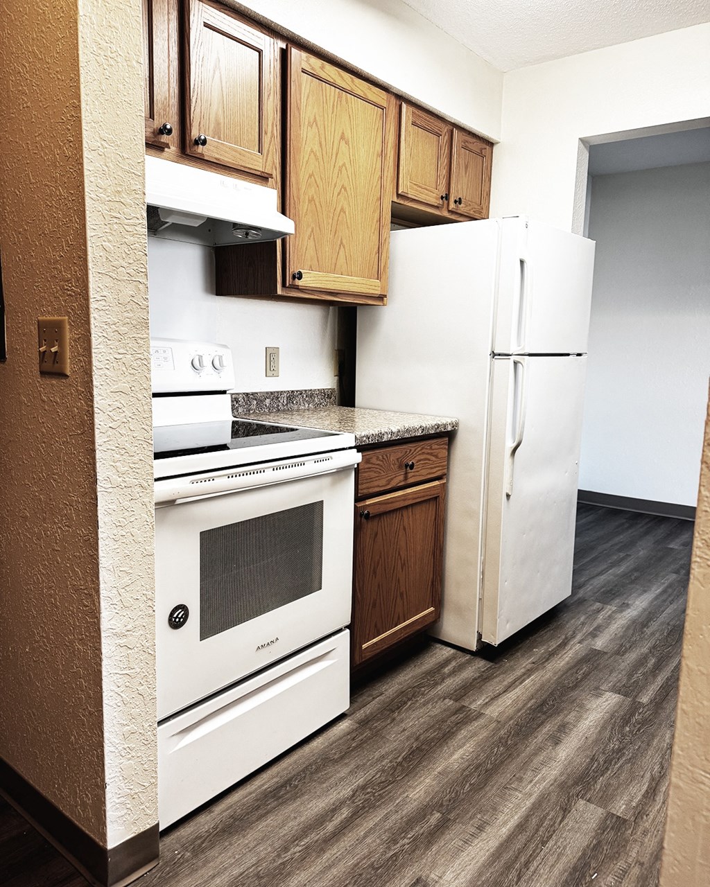 A kitchen with white appliances and wooden cabinets.