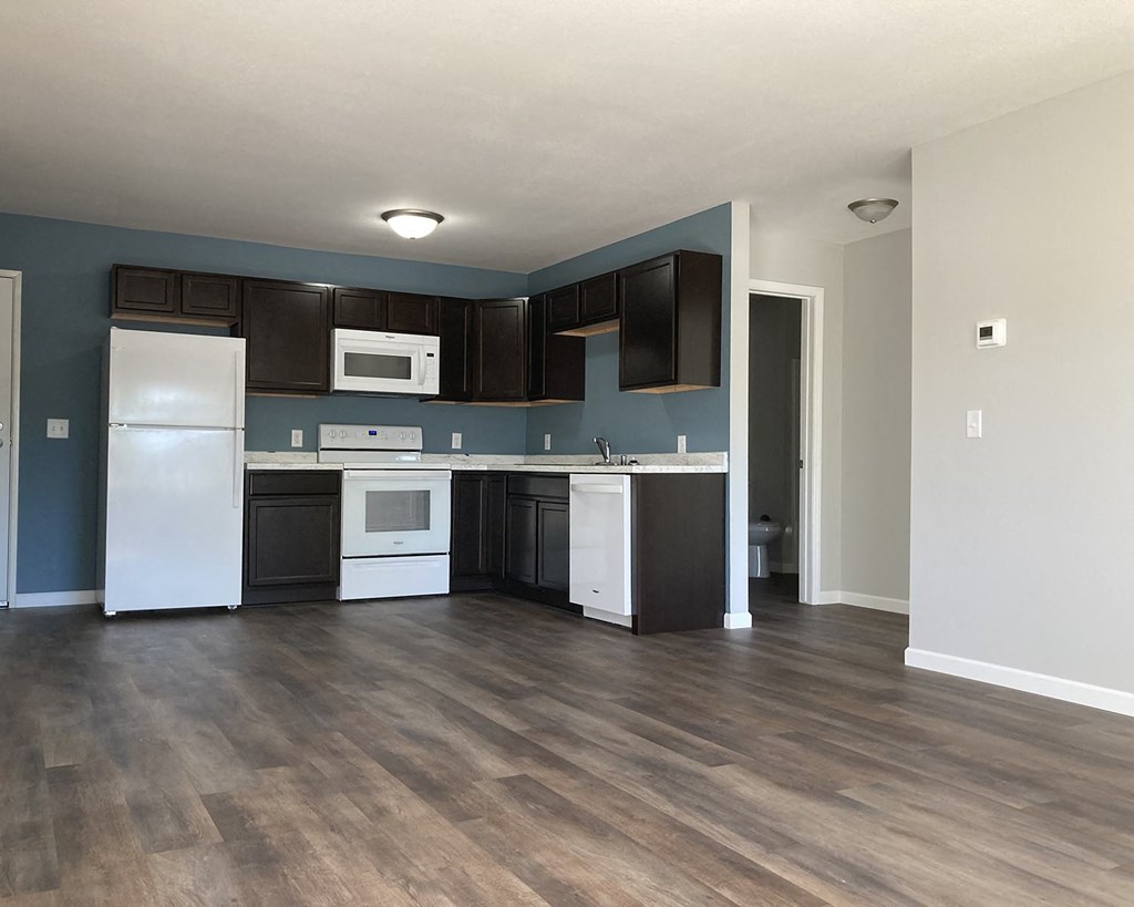 an empty kitchen with white appliances and black cabinets