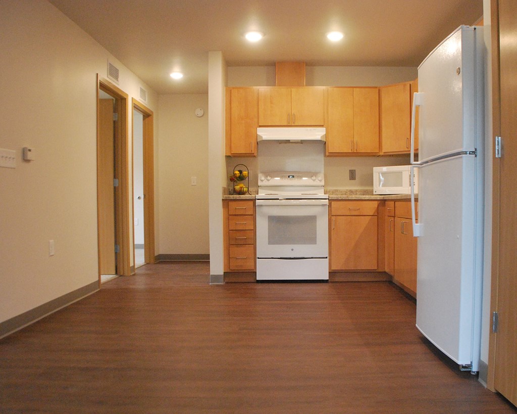 an empty kitchen with wooden cabinets and white appliances