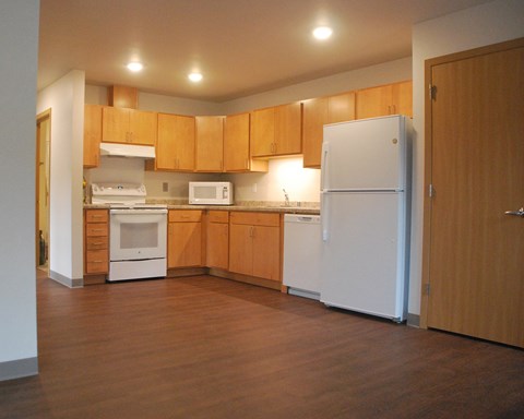 an empty kitchen with wooden cabinets and a white refrigerator