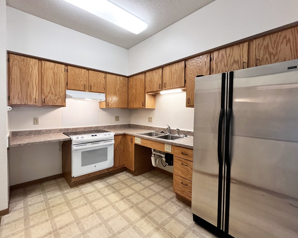 A kitchen with a white refrigerator, white oven, and brown cabinets.