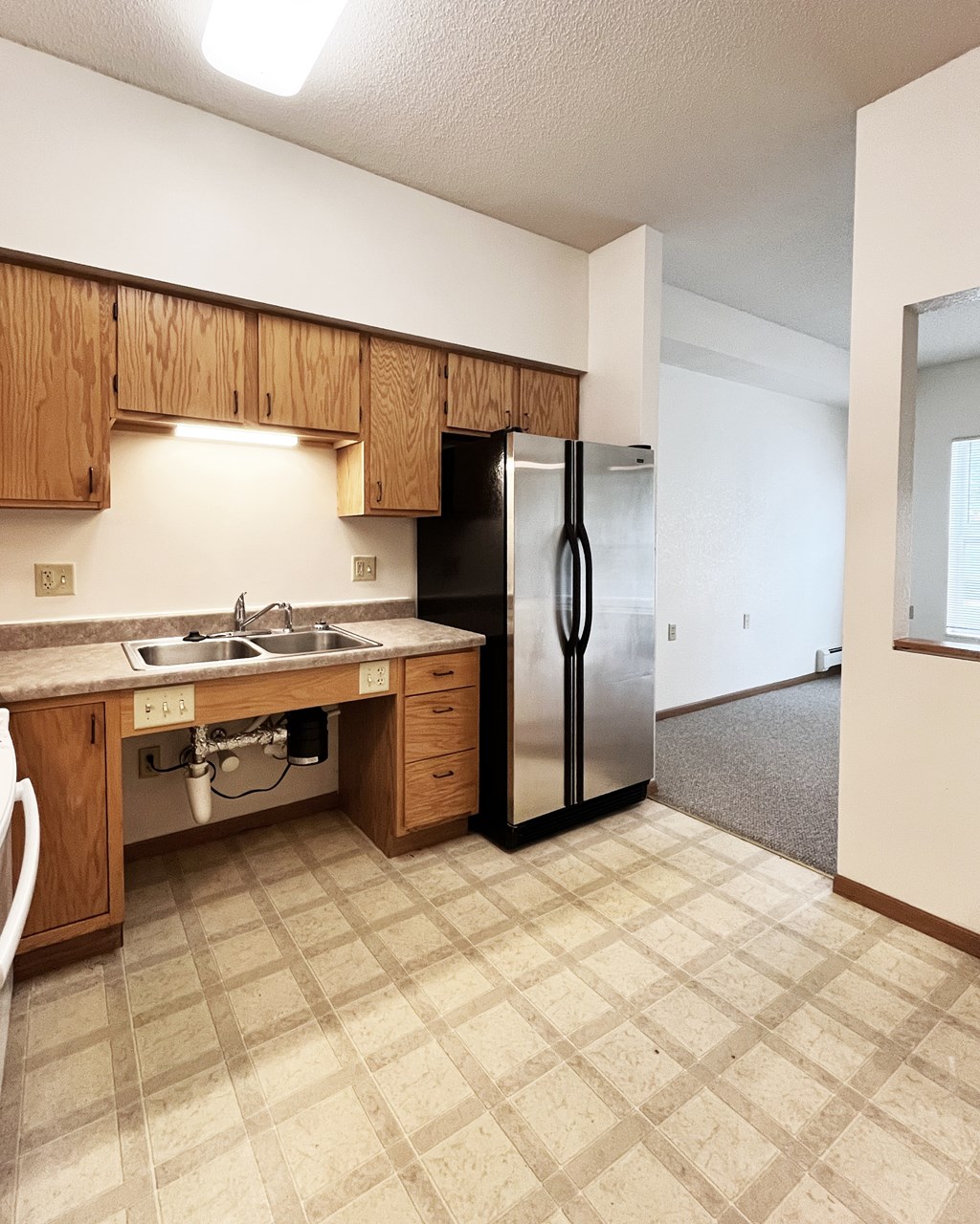 A kitchen with a sink, dishwasher, and refrigerator.