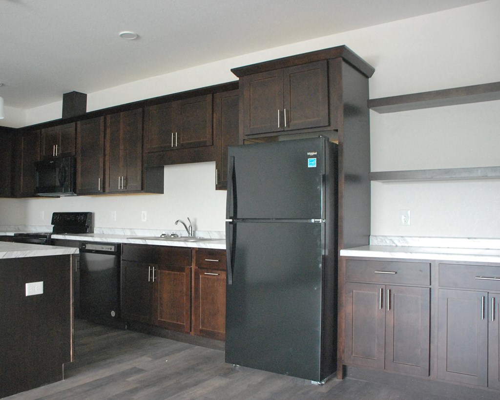 a kitchen with dark wood cabinets and a black refrigerator