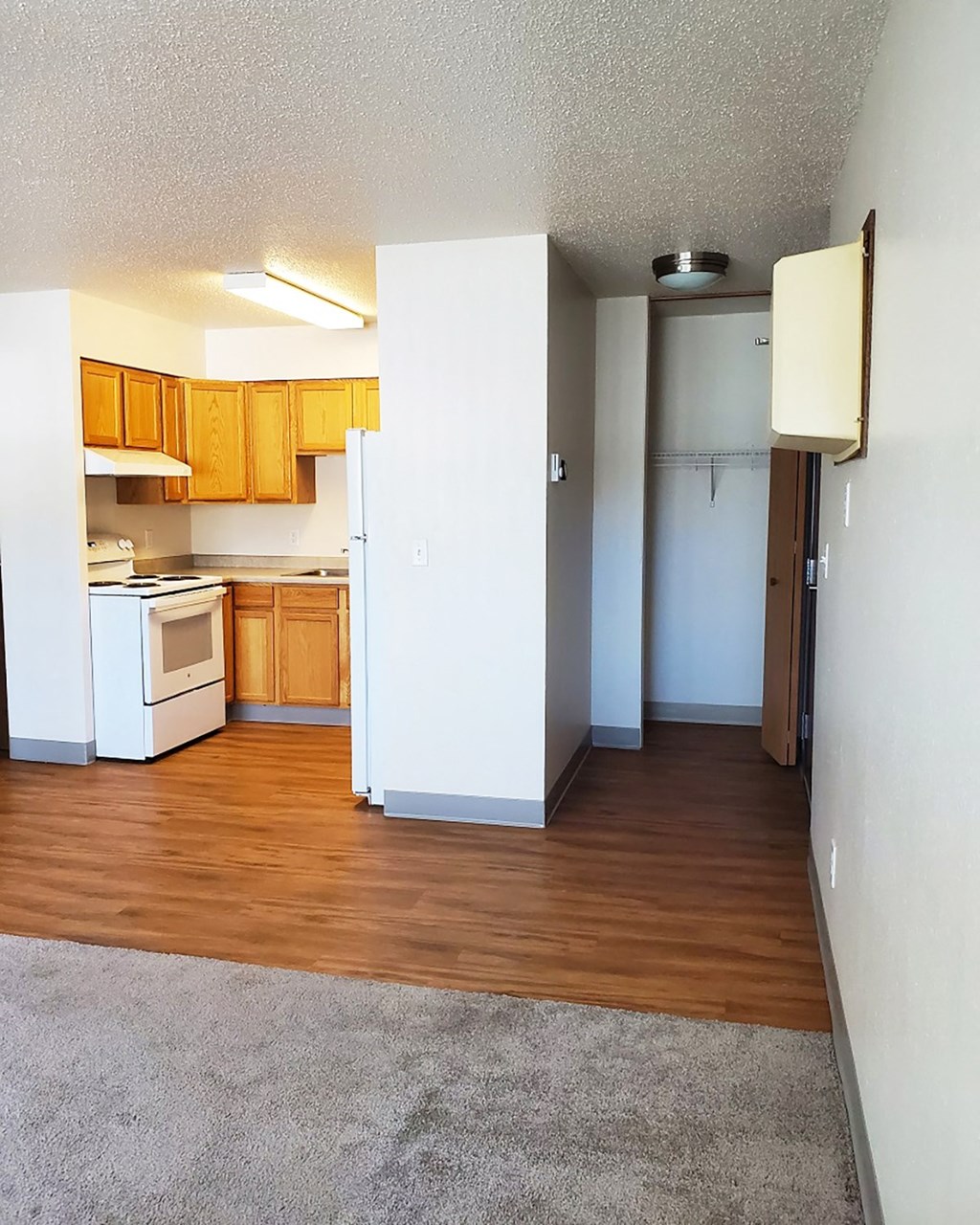 an empty kitchen with wood floors and white appliances