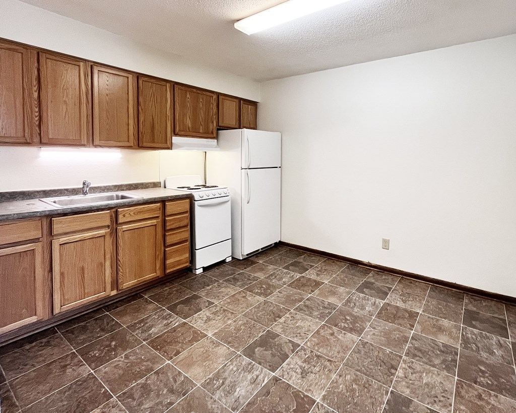 A kitchen with brown cabinets and a white refrigerator.