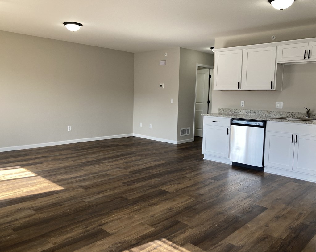 a kitchen and living room with hardwood floors and white cabinets