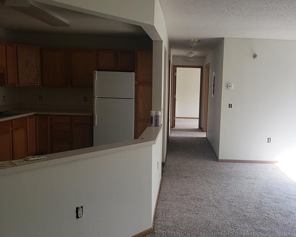 an empty kitchen in an empty house with a refrigerator